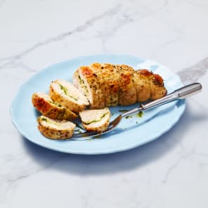 Sliced seasoned chicken breast on a blue plate with a fork