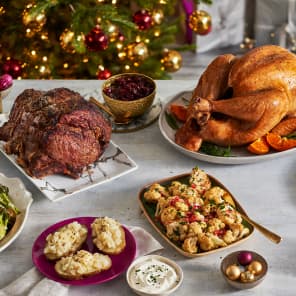 Holiday feast with roasted turkey, prime rib, cauliflower, and side dishes on a decorated table