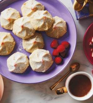 Plate of powdered meringue cookies with raspberries