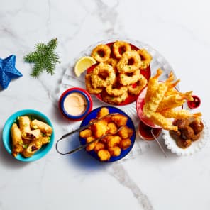 Assorted fried appetizers including calamari, shrimp, cheese sticks, and potatoes with dipping sauce