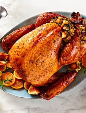 Whole roasted turkey with stuffing, served on a platter with orange slices and herbs